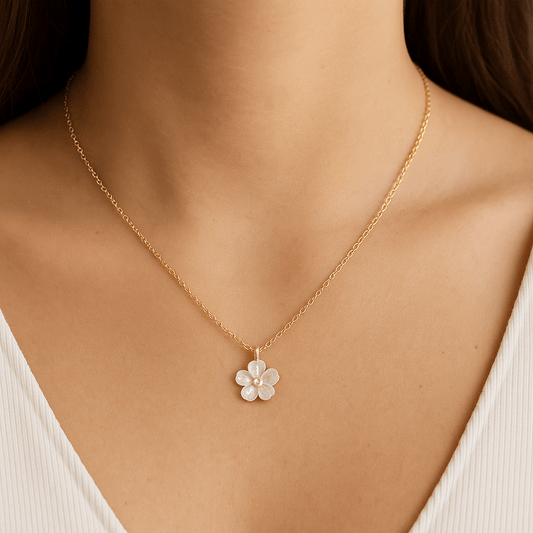 Collier fleur en nacre porté sur chaîne en acier inoxydable doré. Reflets nacrés, chaîne réglable 40–45 cm.